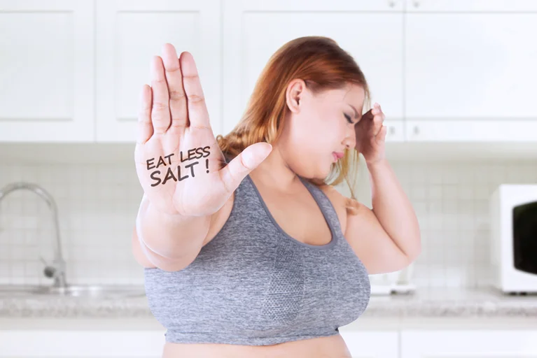 Fat woman shows eat less salt text on her palm.