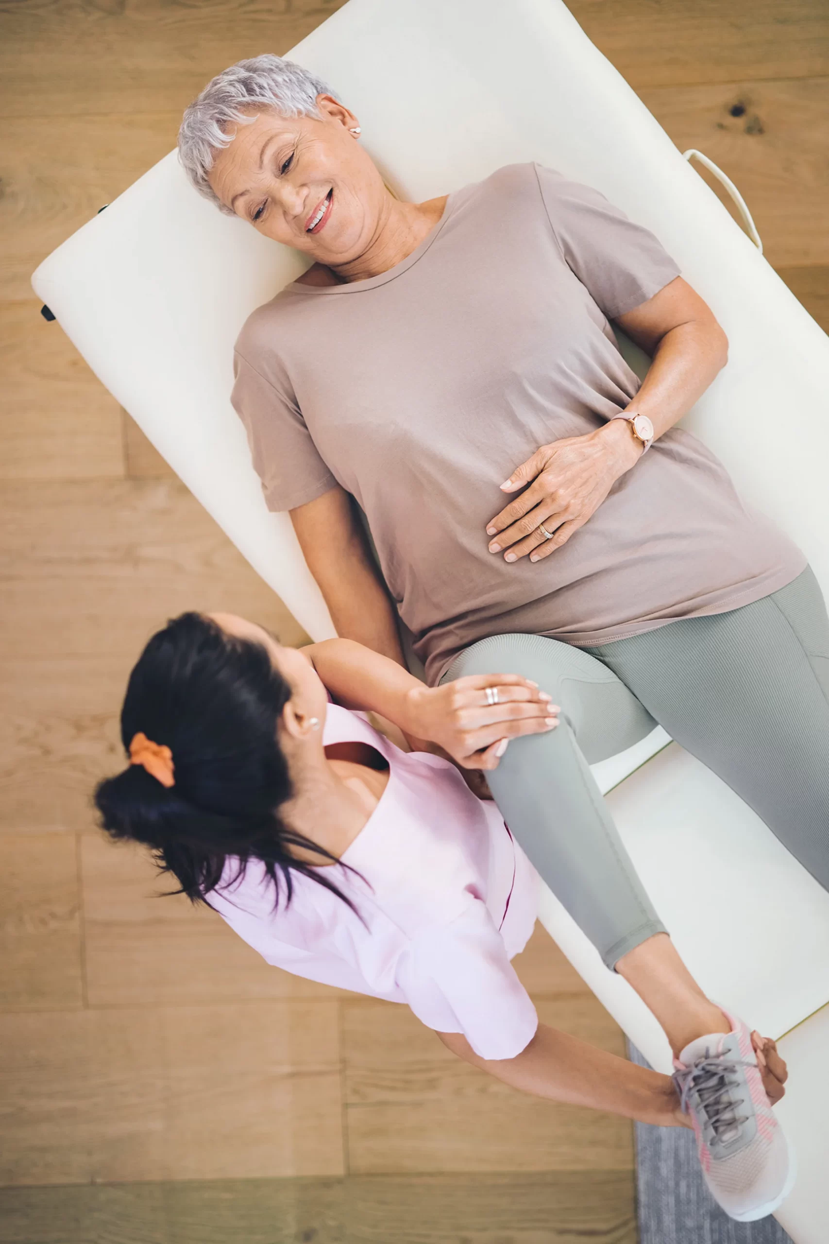 Woman lying down assisted by a Physical Therapist.