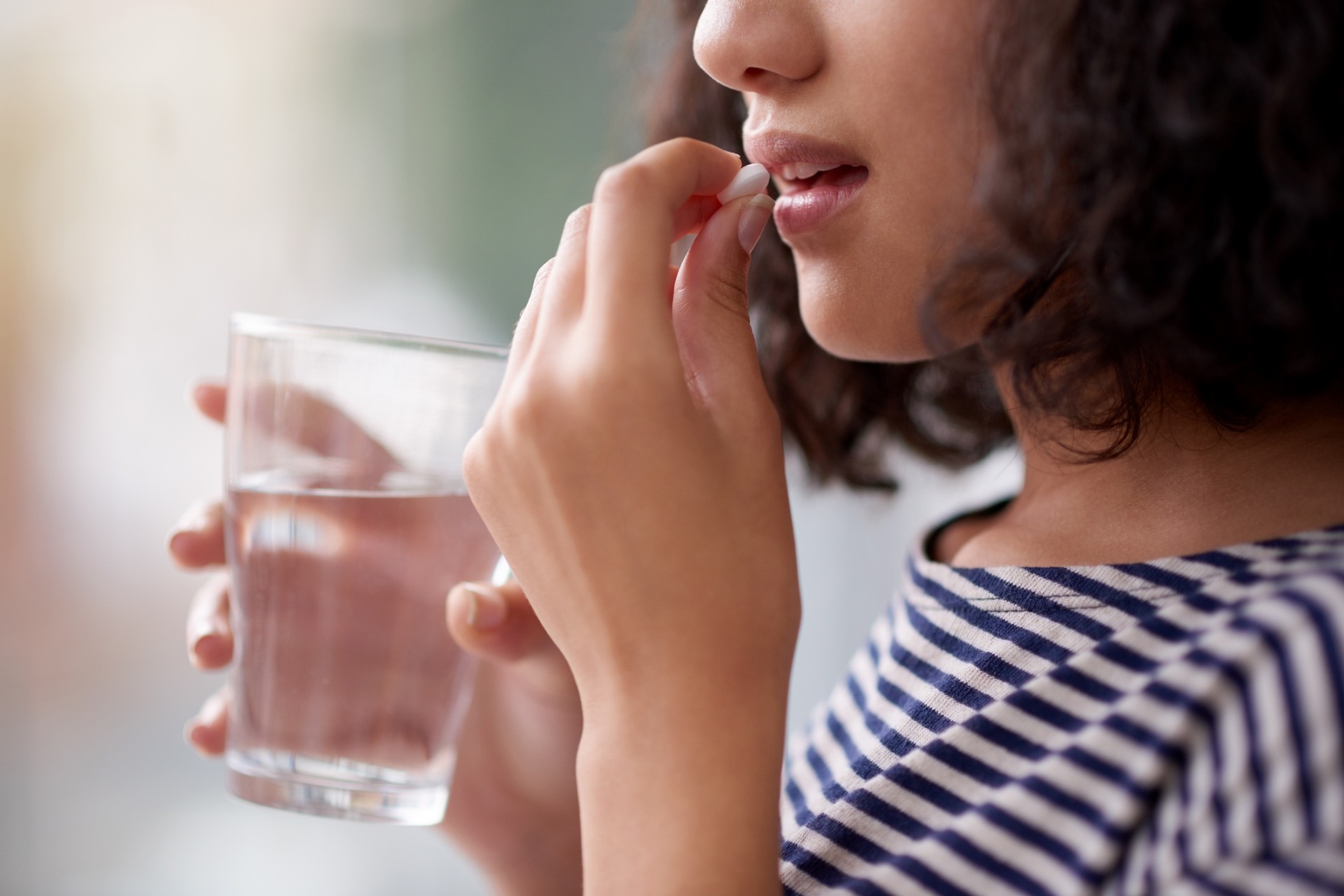 Woman taking supplement pill with water